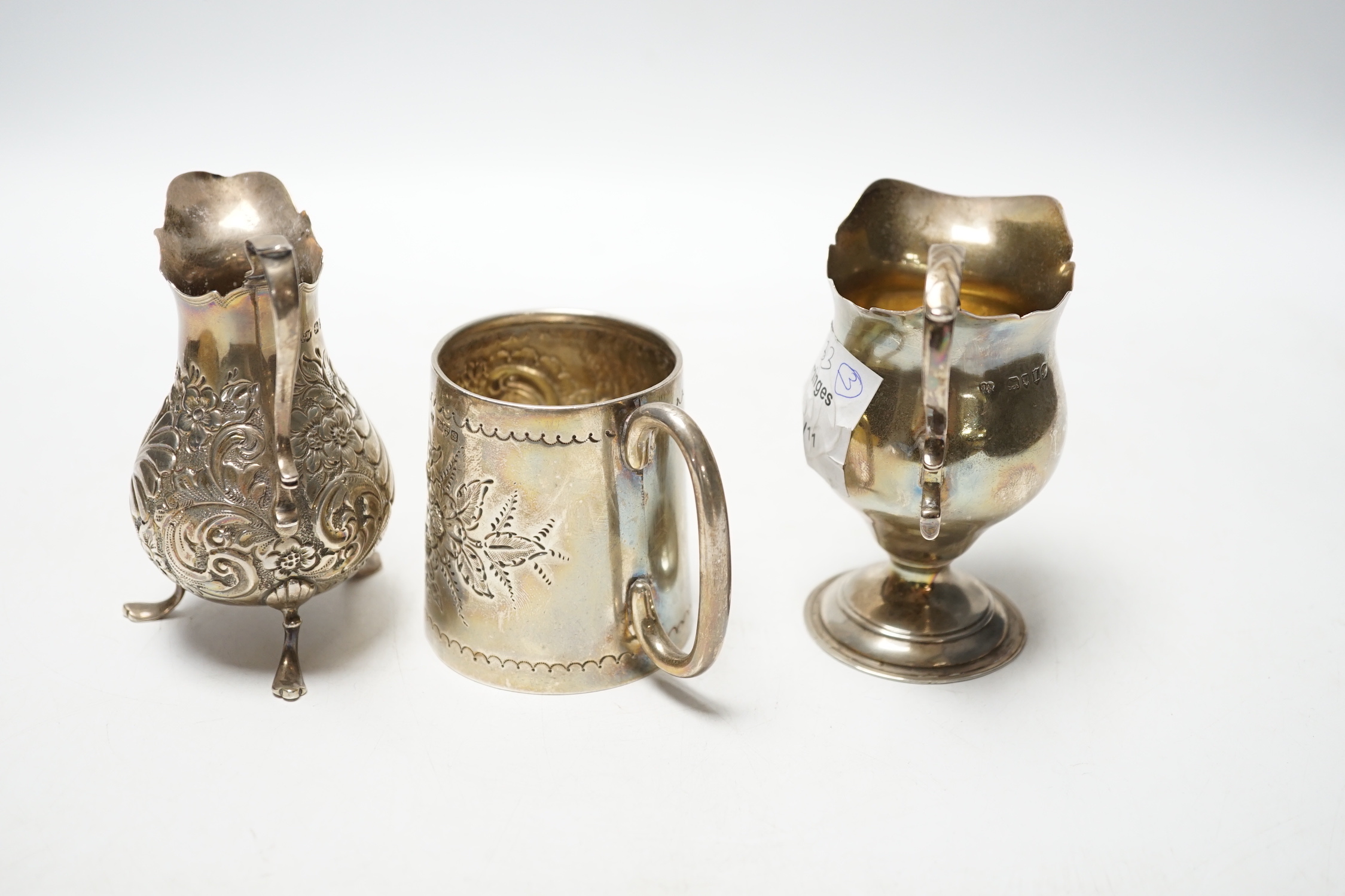 A Victorian silver inverted pyriform cream jug, London, 1886, 10.4cm, another, embossed, Chester, 1896 and an Edwardian silver embossed christening mug, Chester, 1902, 8.1oz.